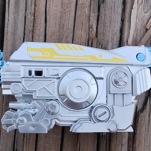 May include: A silver and blue toy robot with a wolf head, yellow accents, and a movable arm. The robot has a detailed design with gears and other mechanical features.