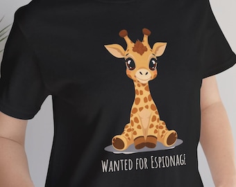 Może przedstawiać: Czarny t-shirt z krótkim rękawem z rysunkową ilustracją siedzącej żyrafy z dużymi oczami i brązowymi plamami. Pod żyrafą znajduje się napis "WANTED FOR ESPIONAGE" białymi wielkimi literami. Koszulka posiada okrągły dekolt.