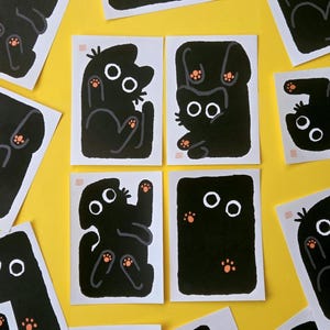 Peut inclure: Une collection d'impressions d'art rectangulaires représentant des chats noirs stylisés sur fond blanc. Chaque illustration utilise des formes noires audacieuses, des yeux circulaires blancs et de petits coussinets orange. Un sceau rouge est visible.