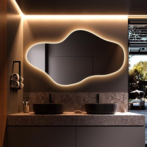 May include: Modern bathroom design featuring a large, organically shaped mirror with a warm, glowing border. The vanity has two black sinks, a stone countertop, and a dark gray cabinet. The space is illuminated by recessed lighting and a view of the outdoors.