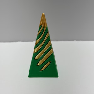 Puede incluir: Un pequeño adorno de árbol de Navidad de forma piramidal verde con remolinos dorados.