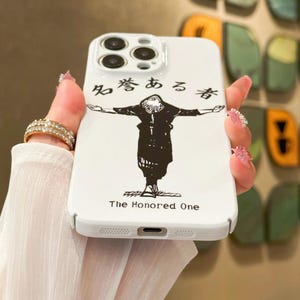 May include: White phone case featuring a black illustration of a figure with outstretched arms. The case has Japanese text and the English text "The Honored One". The case has a camera cutout and button holes.