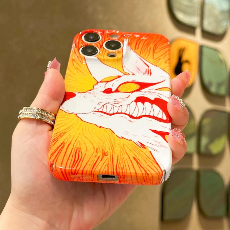 K&ouml;nnte beinhalten: Orange-gelbes Handycase mit einer wei&szlig;en und roten Illustration eines knurrenden Wolfes. Das Case hat eine gl&auml;nzende Oberfl&auml;che und wird in einer Hand gehalten.