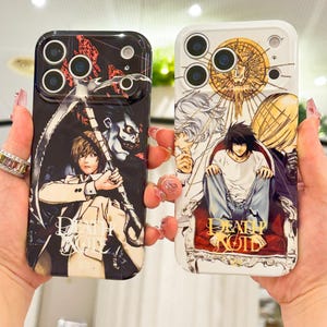 May include: Two smartphone cases featuring Death Note anime graphics. The left case is black with a character holding a scythe. The right case is white with a character sitting on a red chair. Both cases display the Death Note logo in gold text.