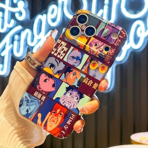 May include: A burgundy phone case featuring a collage of colorful anime-style character illustrations. The case has a glossy finish and a rectangular design, with a camera cutout at the top. The characters have various facial expressions.