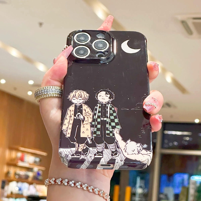 K&ouml;nnte beinhalten: Schwarze Handyh&uuml;lle mit einer Anime-Illustration von zwei Charakteren unter einem Halbmond. Die H&uuml;lle hat eine gl&auml;nzende Oberfl&auml;che und ein detailliertes Design, f&uuml;r Fans der Serie.