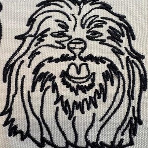 Può includere: Immagine ricamata in bianco e nero di un cane peloso con un grande sorriso. La pelliccia del cane è rappresentata da linee lunghe e fluide.