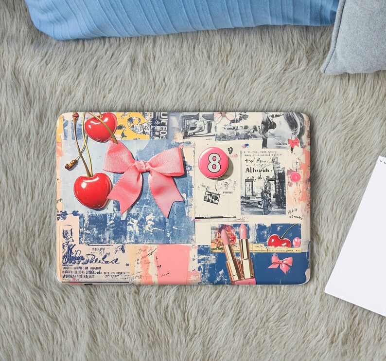K&ouml;nnte beinhalten: Eine rechteckige Laptop-Folie mit einer Collage aus blauen, pfirsichfarbenen und wei&szlig;en Texturen. Sie zeigt zwei rote Kirschen, eine gro&szlig;e rosa Stoffschleife, einen rosa Knopf mit der Zahl 8, ein Schwarz-Wei&szlig;-Foto und zwei rosa Lippenstifte.