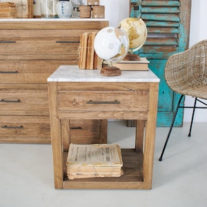 Op de afbeelding: Een houten nachtkastje met een marmeren blad en een lade. Twee globes staan erop. Een stapel oude papieren staat op de onderste plank. Een houten dressoir staat op de achtergrond.