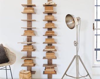 Peut inclure: Deux étagères murales en bois remplies de piles de livres anciens, attachés avec de la ficelle. Un lampadaire trépied argenté se trouve à proximité. Un fauteuil en osier avec un coussin sombre est dans le coin. Ambiance vintage.