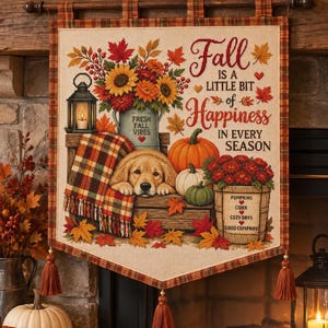 Op de afbeelding: Een rechthoekige stoffen wandhanger met een geruite rand en drie kwastjes. Het ontwerp toont een golden retriever puppy, pompoenen, een lantaarn en een boeket zonnebloemen. De tekst luidt: Fall is a little bit of happiness in every season.