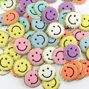 May include: A collection of colourful, fuzzy smiley face patches with gold trim. The patches are perfect for adding a fun and cheerful touch to clothing, bags, or other accessories.