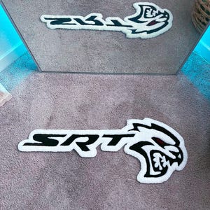 Può includere: Tappetino da pavimento bianco con scritta SRT nera e logo Dodge Challenger nero e rosso.