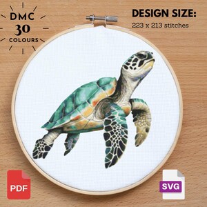 May include: A cross-stitch embroidery hoop featuring a sea turtle design. The turtle has a green and yellow shell, with black and white patterned flippers. The design size is 223 x 213 stitches. The text "DMC 30 COLOURS" is visible.
