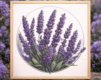 May include: A framed cross-stitch of lavender flowers in a circular design. The purple flowers have green stems and leaves, set against a white background. The frame is made of light-colored wood, and the artwork is hanging by a natural fiber cord.