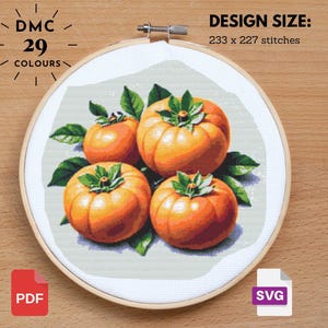 May include: Cross-stitch design featuring four orange persimmons with green leaves, displayed in a wooden embroidery hoop. The design size is 233 x 227 stitches, with 29 colors. Includes PDF and SVG file formats.