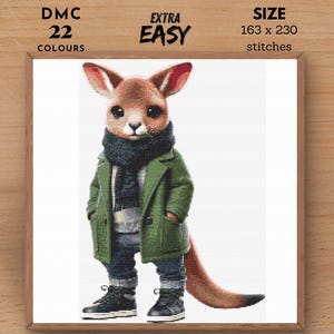 Puede incluir: Un patrón de punto de cruz con un canguro de dibujos animados que lleva un abrigo verde, una bufanda y botas marrones. El patrón está etiquetado como "EXTRA EASY" y requiere 22 colores y 163 x 230 puntos.