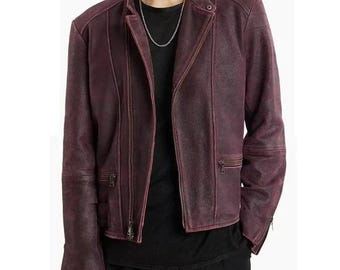May include: A burgundy leather jacket with a classic asymmetrical zipper design. The jacket features a notched collar, multiple zippered pockets, and a textured finish. The jacket is worn over a black shirt and a silver chain.
