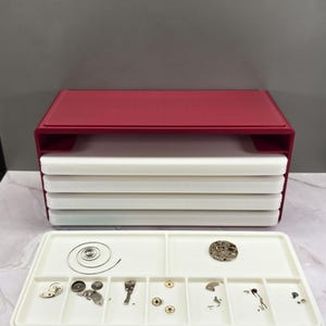 May include: A white ceramic mug with a black handle and the text "But First, Coffee" in a bold, black font. The mug is set against a blurred background, suggesting a cozy setting. The mug appears to be approximately 4 inches tall.