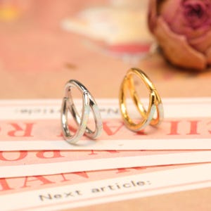 May include: Two hoop earrings with a white opal inlay. The hoop on the left is silver and the hoop on the right is gold.