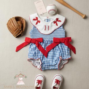 May include: A baseball-themed baby outfit set, featuring a blue and white gingham romper with red bows, a baseball, a bat, a baseball glove, and white sneakers with red laces. The romper has a white collar with red trim and bow accents.