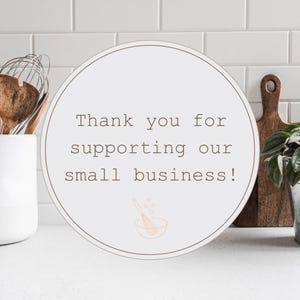 May include: White round sign with brown text that says "Thank you for supporting our small business!" with a small illustration of a mixing bowl and whisk.