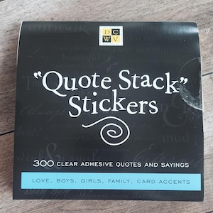 Puede incluir: Un juego de pegatinas Quote Stack negras con texto blanco, que incluye las palabras "Quote Stack Stickers" y "300 citas y refranes adhesivos transparentes". Una pancarta azul claro en la parte inferior enumera "Love, Boys, Girls, Family, Card Accents."