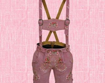 Puede incluir: Pantalones de cuero rosas con bordados florales. Los tradicionales pantalones cortos bávaros presentan tirantes con hebillas decorativas y detalles florales bordados. Los pantalones cortos tienen bolsillos y están hechos de un material similar al ante. Los tirantes son de un rosa más claro con la parte trasera marrón.