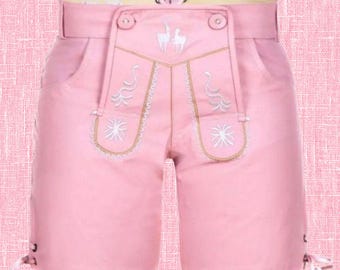 Puede incluir: Pantalones cortos de cuero rosa claro con una solapa frontal tradicional con bordados blancos de ciervos y motivos florales. La prenda incluye una cintura con trabillas, bolsillos laterales y detalles de cordones decorativos en las costuras.