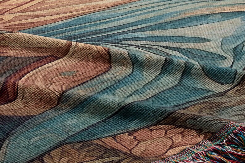 Puede incluir: Primer plano de una manta de tejido de tapiz con un patr&oacute;n floral azul, marr&oacute;n y naranja. La manta tiene un borde de flecos.