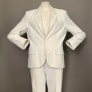 May include: A white suit with a single-breasted blazer and matching pants. The blazer has a notched lapel and two button closure. The pants have a straight leg.