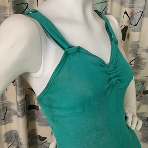 Pu&ograve; includere: Un top senza maniche blu turchese con scollo rotondo e spalline regolabili. Il top presenta un dettaglio arricciato sul seno.