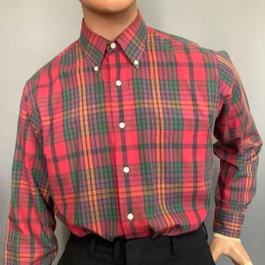May include: A red, green, and orange plaid long-sleeve button-down shirt.