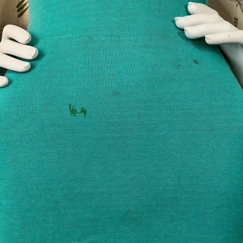 Pu&ograve; includere: Un tessuto a costine blu turchese con due piccole macchie verde scuro.