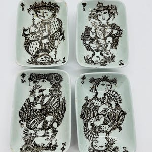 May include: Four rectangular, light green ceramic dishes with black playing card illustrations. Each dish features a different playing card figure, including a king and queen. The dishes have a slightly distressed appearance.