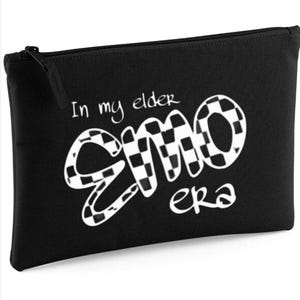 Op de afbeelding: Zwarte etui met ritssluiting met de witte tekst "In my elder EMO era". Het woord "EMO" is gestileerd met een zwart-wit geblokt patroon. De etui heeft een zwarte ritssluiting.