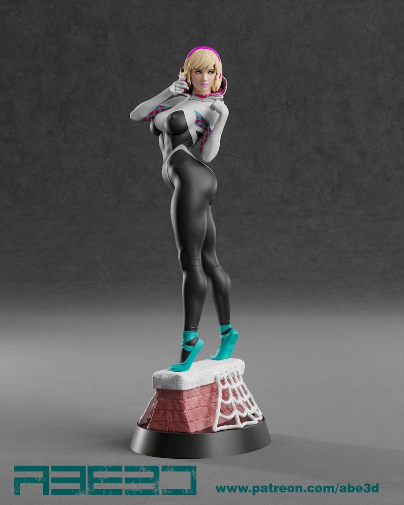 Op de afbeelding: Een 3D-geprinte figuur van een vrouwelijke superheld in een zwart en wit pak met een spinnenwebontwerp. De figuur heeft blond haar en draagt ​​turkooiskleurige hakken. De basis is een schoorsteen met een spinnenwebontwerp en de tekst "ABE3D" en "www.patreon.com/abe3d".