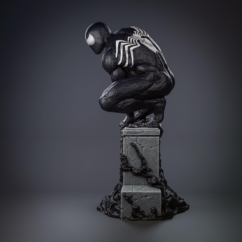 May include: A black and white statue of a crouching superhero, with a white spider emblem on the back. The figure is on a gray, textured pedestal with dark, organic details. The statue has a detailed, muscular physique.