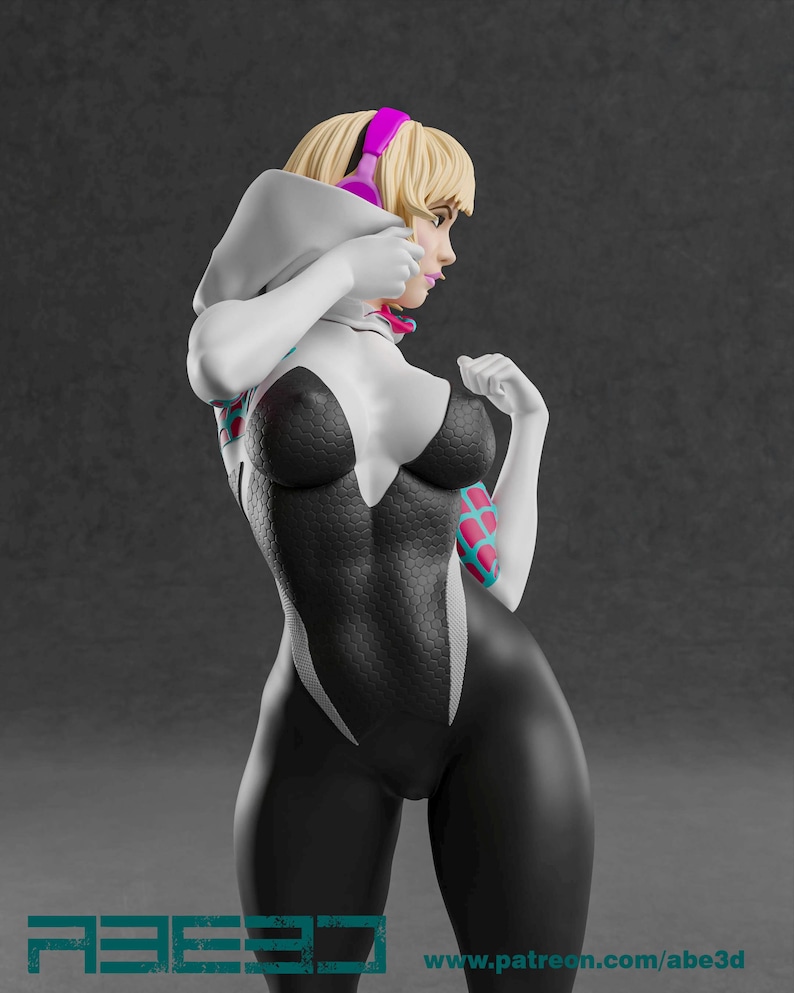 Op de afbeelding: Een 3D-gefigureerde figuur van een vrouwelijke superheld in een zwart-wit bodysuit met een spinnenwebpatroon. Ze heeft blond haar, roze koptelefoon en een witte hoodie. De figuur poseert met haar handen omhoog.