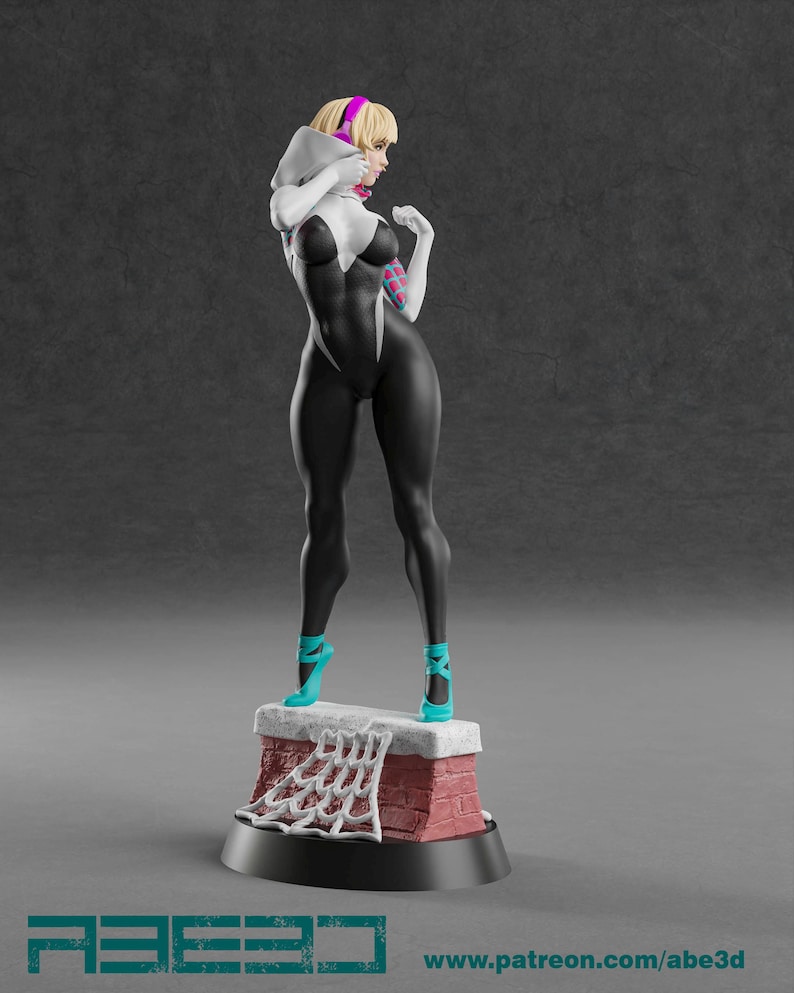 Op de afbeelding: 3D-geprinte beeldje van een vrouwelijke superheldin in een zwart-wit bodysuit, staand op een bakstenen structuur. Ze heeft blond haar, een roze haarband en turquoise hakken. De basis heeft de tekst "ABE3D" en een websiteadres.