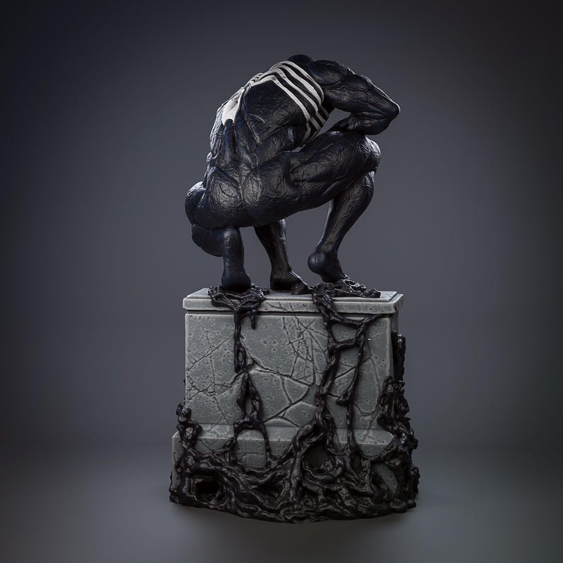 May include: A black and white Venom statue in a crouching position atop a grey stone pedestal. The statue has a detailed muscular physique and a white spider emblem on its chest. Black tendrils wrap around the pedestal.