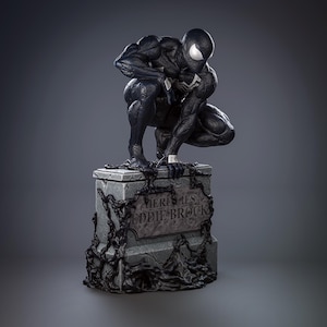 May include: A black and white Spider-Man statue in a crouching pose atop a stone tombstone. The tombstone reads "Here Lies Eddie Brock" in white lettering. Black tendrils and chains wrap around the tombstone.