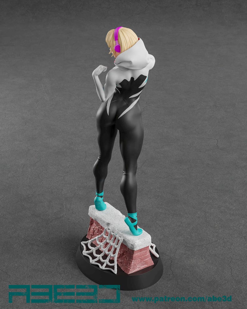 Op de afbeelding: Figuur van een personage in een zwart-wit bodysuit met een spinnenwebontwerp, een witte hoodie en turquoise schoenen. De figuur heeft blond haar en een roze koptelefoon. De basis heeft een bakstenen ontwerp en een wit spinnenweb.