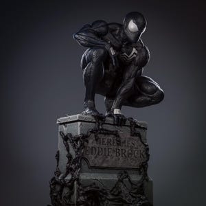 May include: A black and white statue of a superhero in a crouching position atop a tombstone. The tombstone reads "HERE LIES EDDIE BROCK" and is covered in dark vines. The superhero is wearing a black suit with white accents.