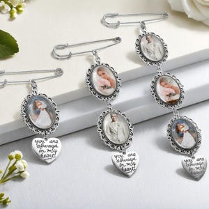 Può includere: Tre spille commemorative argentate con cornici ovali per foto e ciondoli a forma di cuore. Ogni spilla presenta foto incorniciate e un ciondolo a forma di cuore con la scritta "You are always in my heart!"