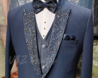 Può includere: Una giacca di abito blu scuro con revers in raso nero decorato con strass scintillanti. La giacca ha una chiusura con un solo bottone e una tasca sul lato sinistro.