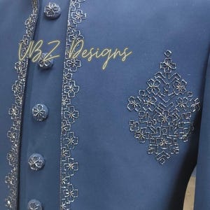 Puede incluir: Chaqueta azul marino con intrincados bordados florales plateados en el cuello, el frente y un dise&ntilde;o en el pecho. La chaqueta presenta botones plateados a juego y el texto "BZ Designs".