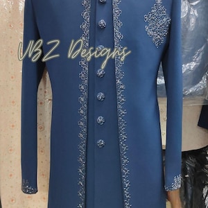 Puede incluir: Una larga chaqueta formal azul marino con intrincados bordados plateados en los bordes, el cuello y los pu&ntilde;os. La chaqueta presenta una fila de botones a juego y un dise&ntilde;o decorativo en el pecho. El texto "VBZ Designs" es visible.