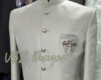 Puede incluir: Chaqueta verde claro con estampado geométrico, cuello mao y botones decorativos. Tiene un bolsillo con broche y el texto "UBZ Designs" en cursiva.
