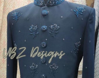 Puede incluir: Chaqueta formal azul marino con intrincados bordados florales y adornos. La chaqueta presenta un cuello mandarín y botones decorativos. El texto "VBZ Designs" es visible en la parte inferior izquierda.